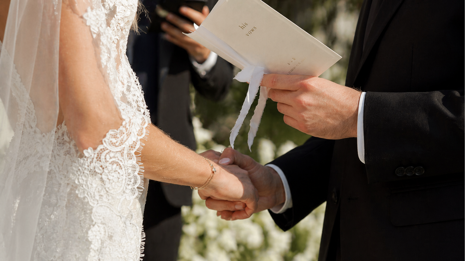Groom holding vow booklet and bride’s hand during wedding ceremony