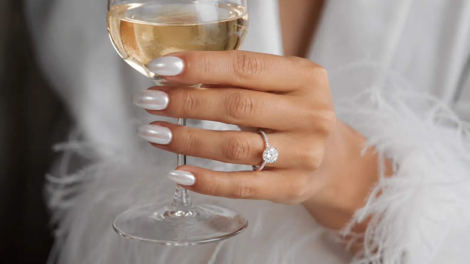 Chrome white wedding nails holding a champagne glass at bridal celebration