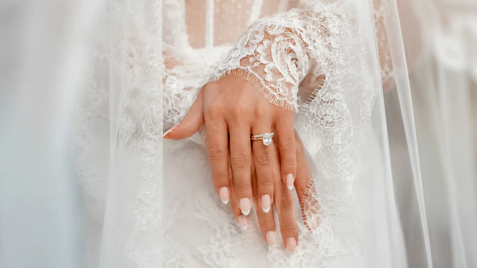 French tip wedding nails with lace bridal sleeves and diamond ring