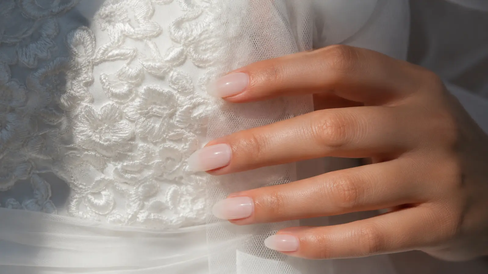 Milky white bridal nails close-up with lace wedding dress details
