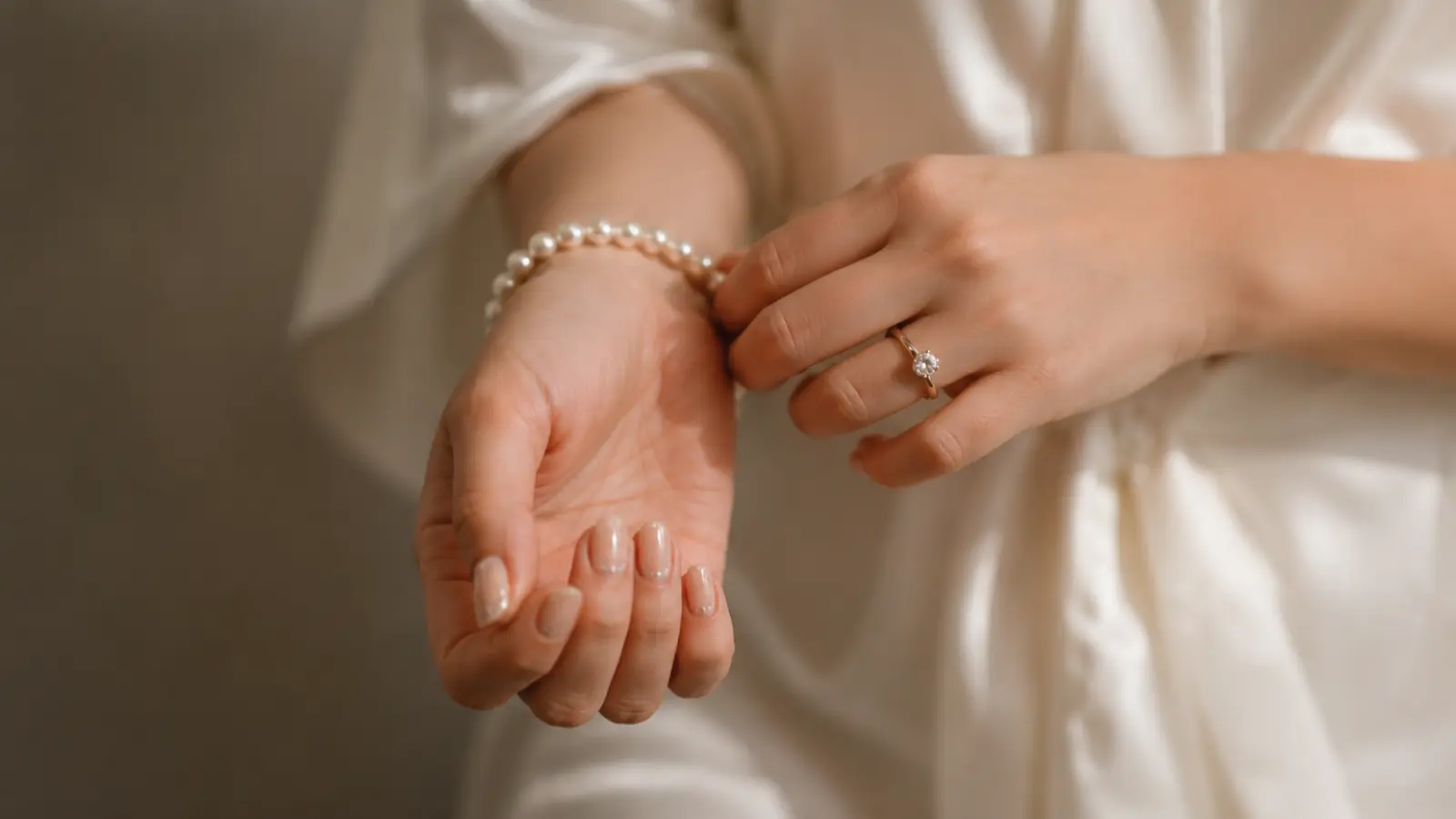 Minimal nude simple wedding nails with pearl bracelet and bridal robe