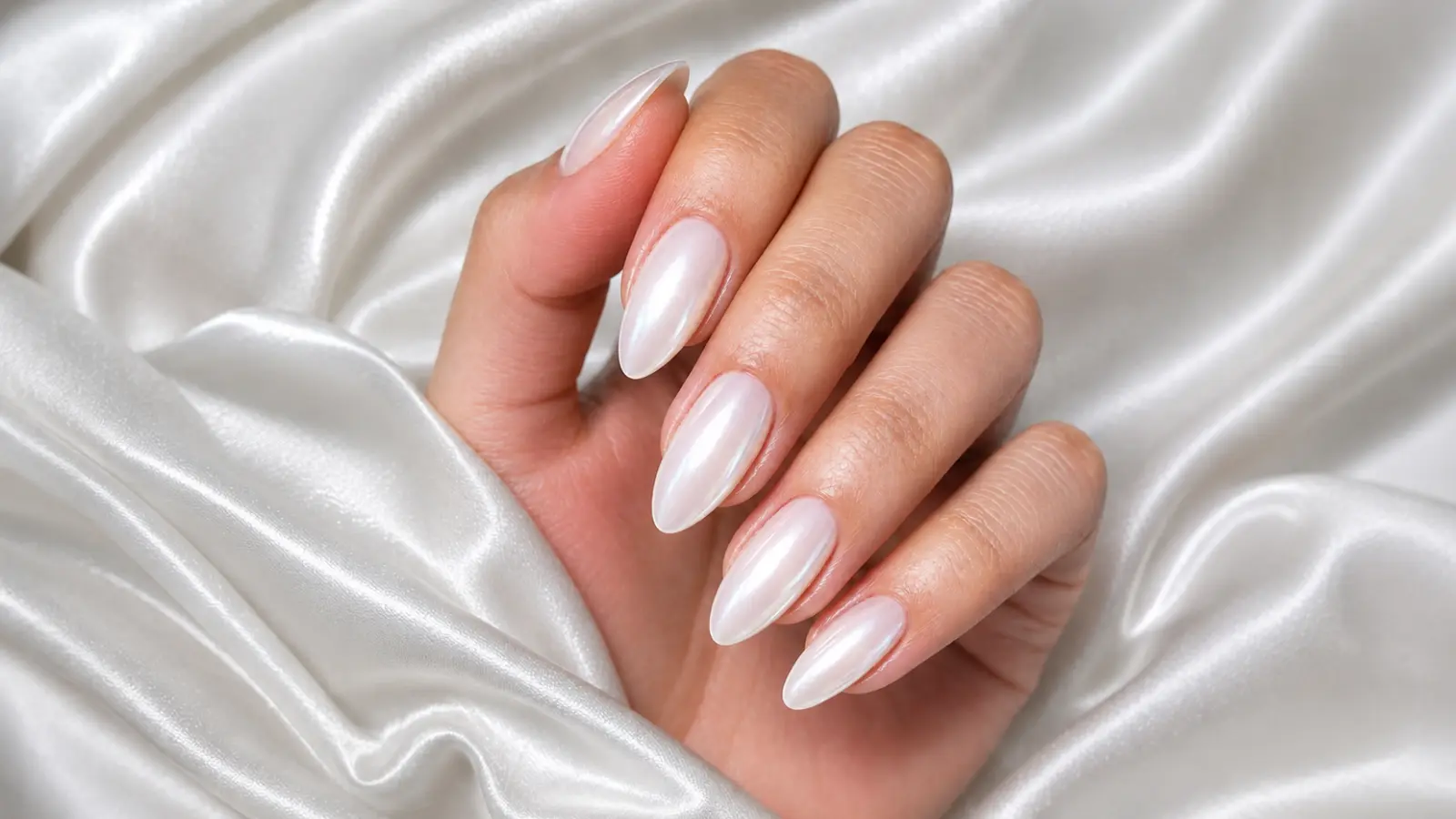 Pearl chrome bridal wedding nails with glossy white shimmer on satin fabric