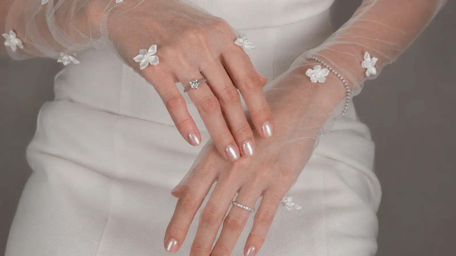 Pearl chrome wedding guest nails with sheer floral gloves and silver rings
