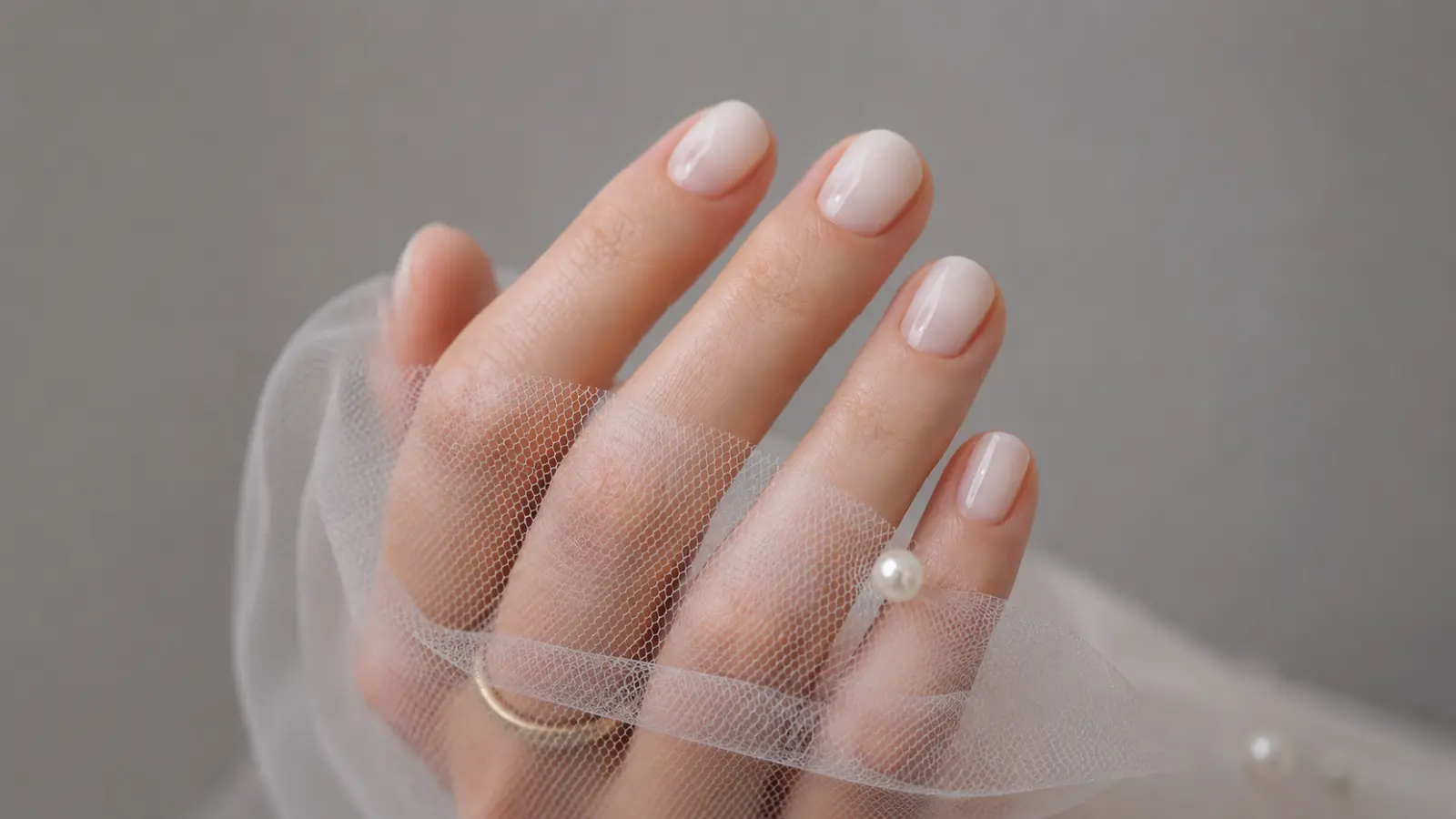 Short simple wedding nails with soft blush polish and bridal tulle