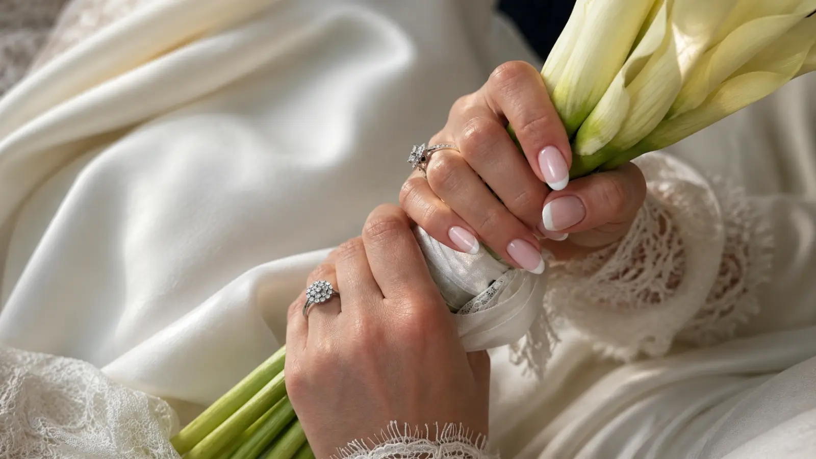 Simple French tip wedding nails holding a white bridal bouquet