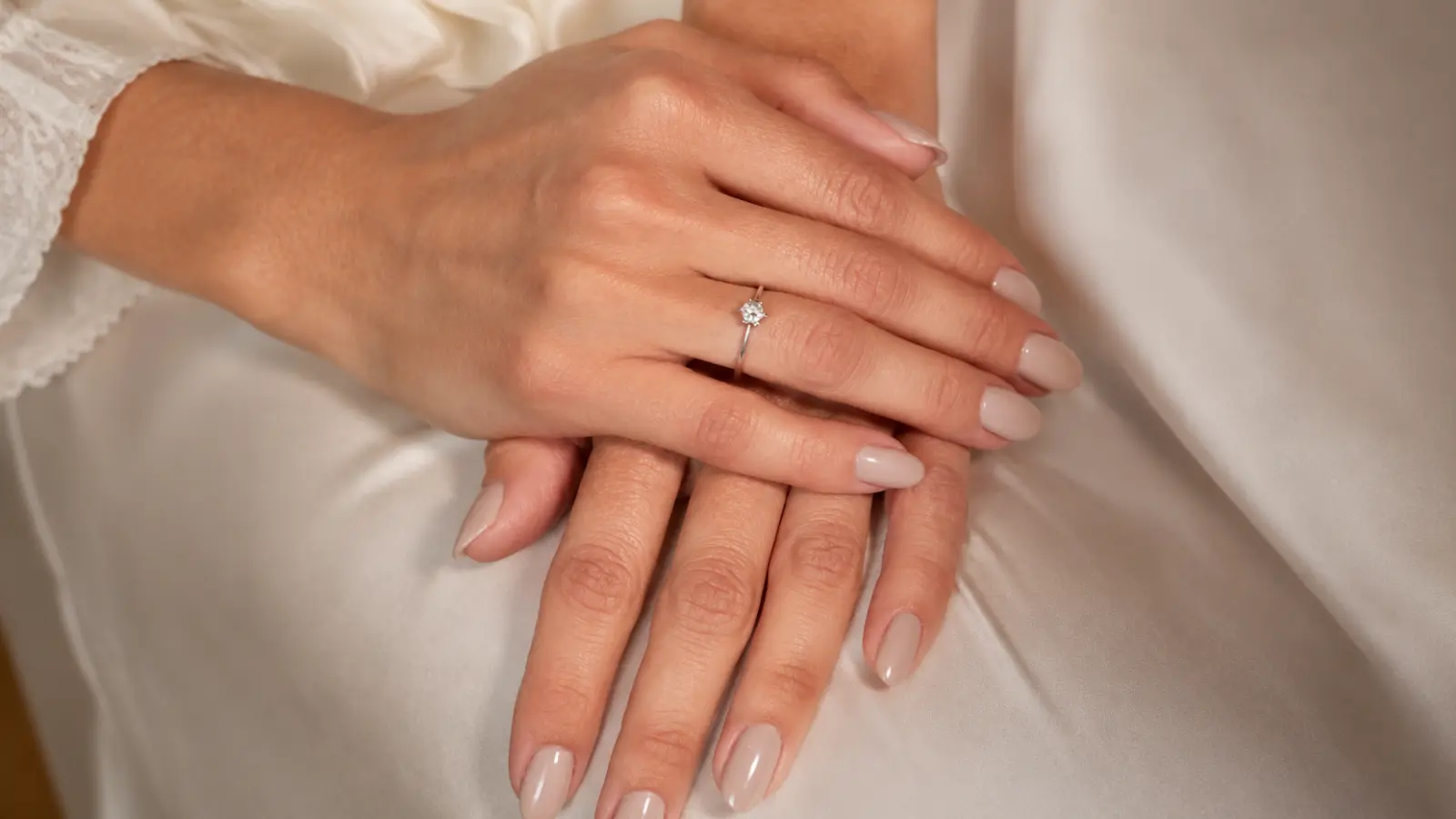 Soft nude wedding guest nails with satin fabric and delicate ring