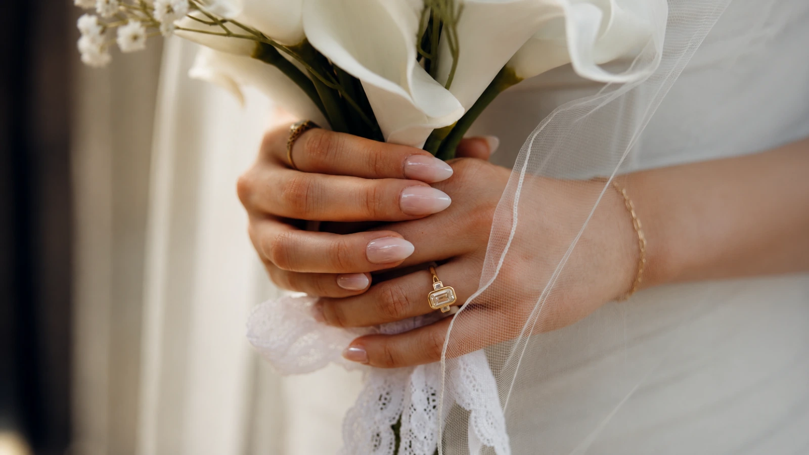 Soft pink wedding nails holding a white bridal bouquet