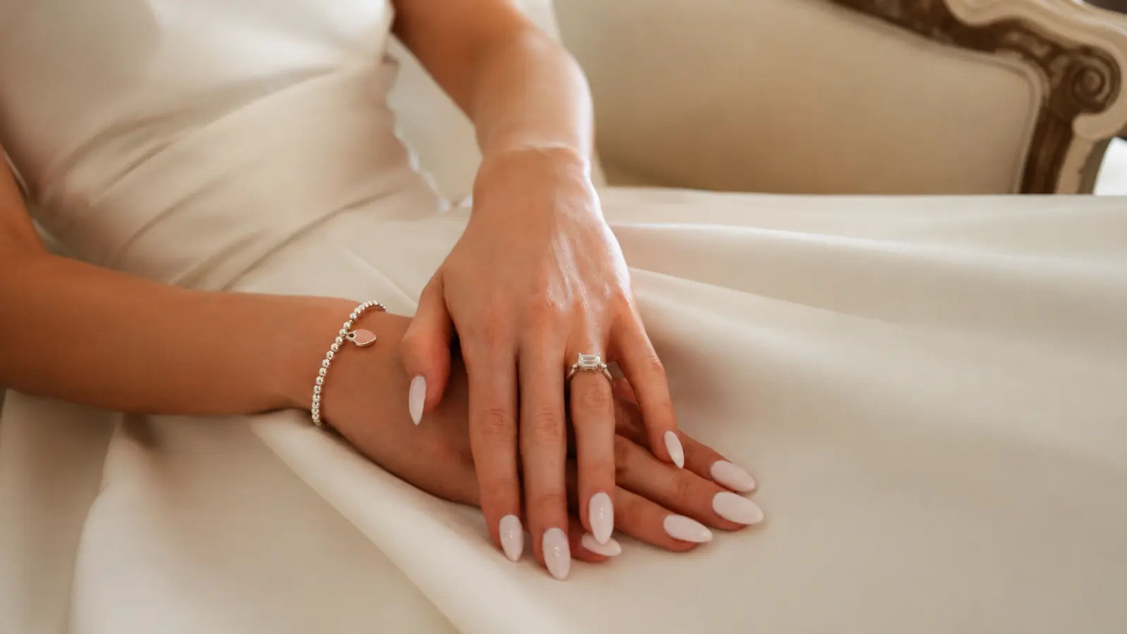 White bridal nails with satin wedding dress and diamond engagement ring