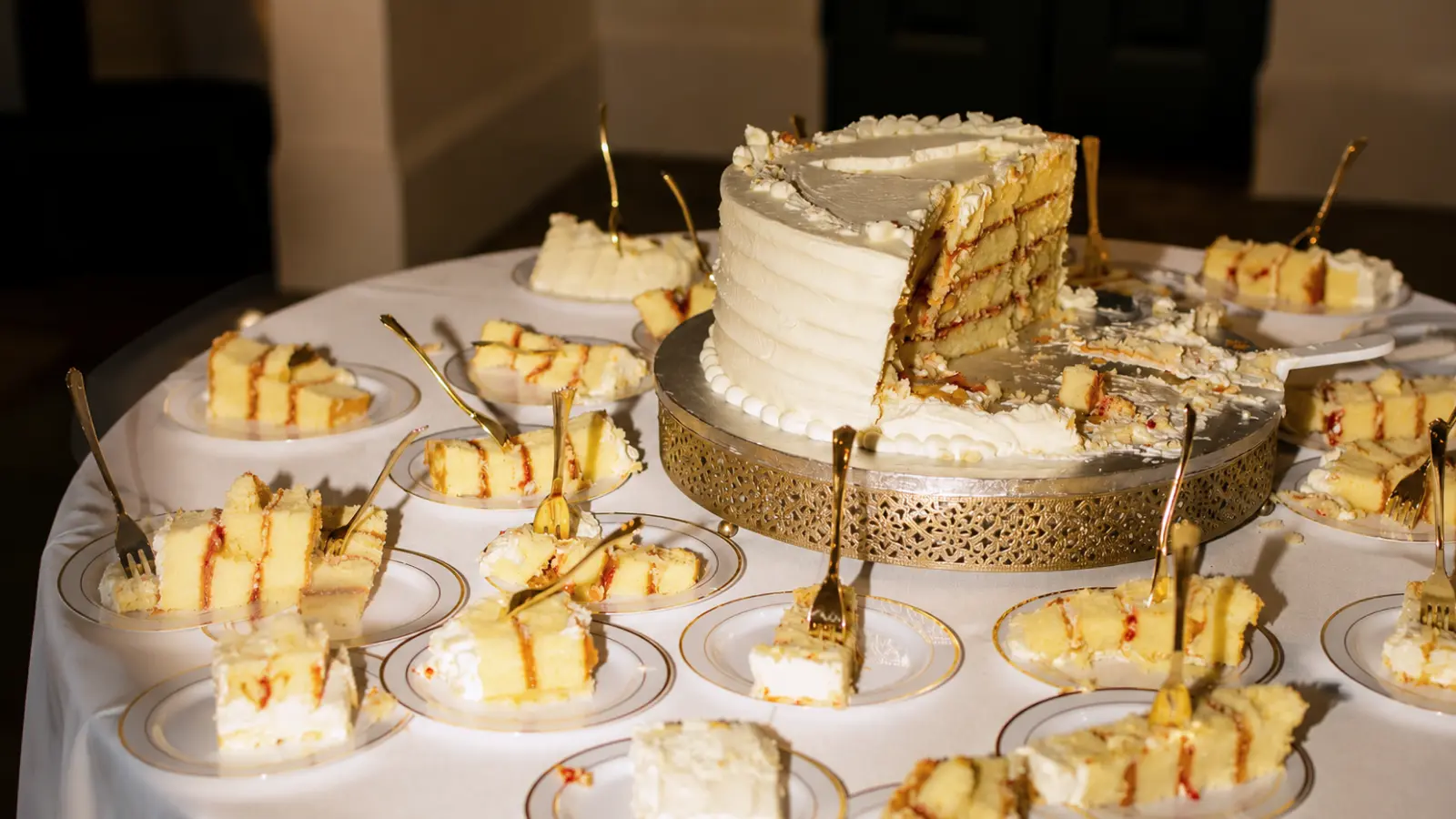 udget wedding cake serving table with multiple cake portions, classic white cake layers, individual plates, and affordable wedding dessert ideas.