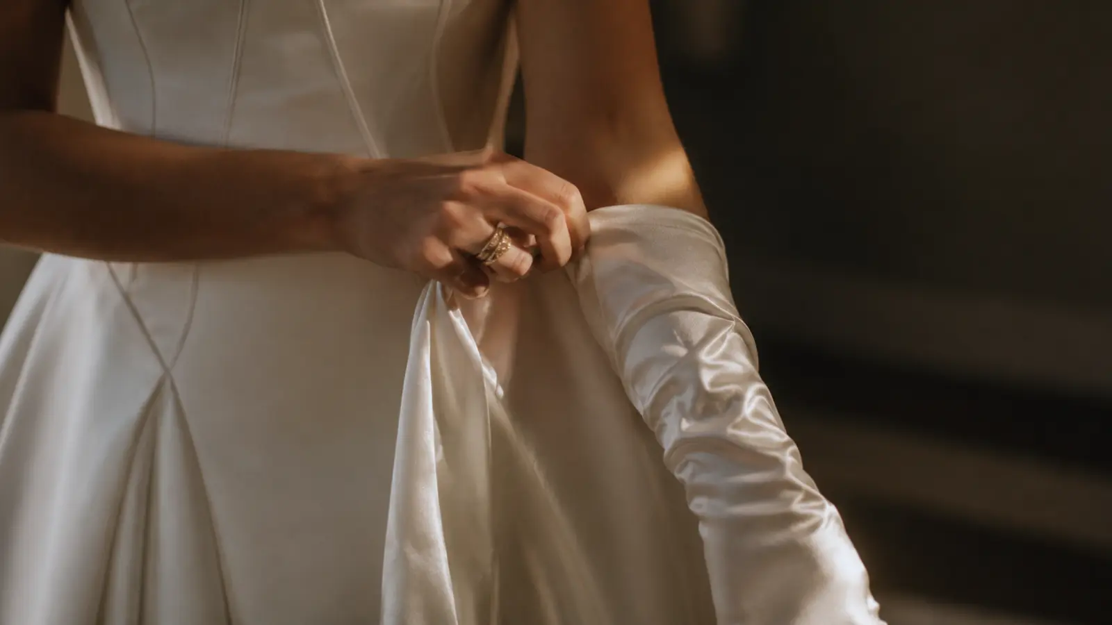 Bride putting on long satin bridal gloves with a wedding dress, highlighting a classic way to style gloves for the ceremony