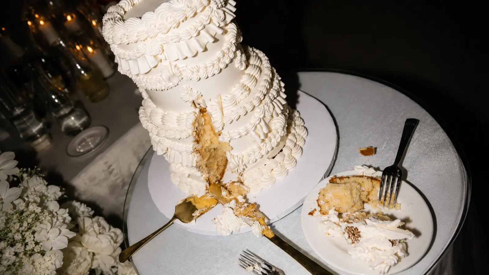 Classic white wedding cake slices with vanilla layers, buttercream filling, gold forks, and simple traditional wedding cake flavors.