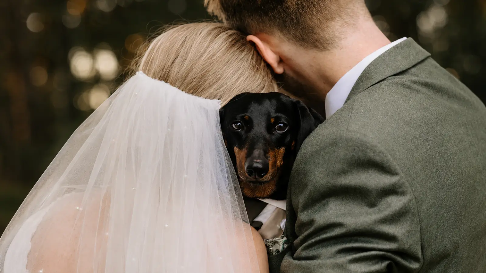 Bride and groom hugging their dachshund while taking an intimate wedding photo