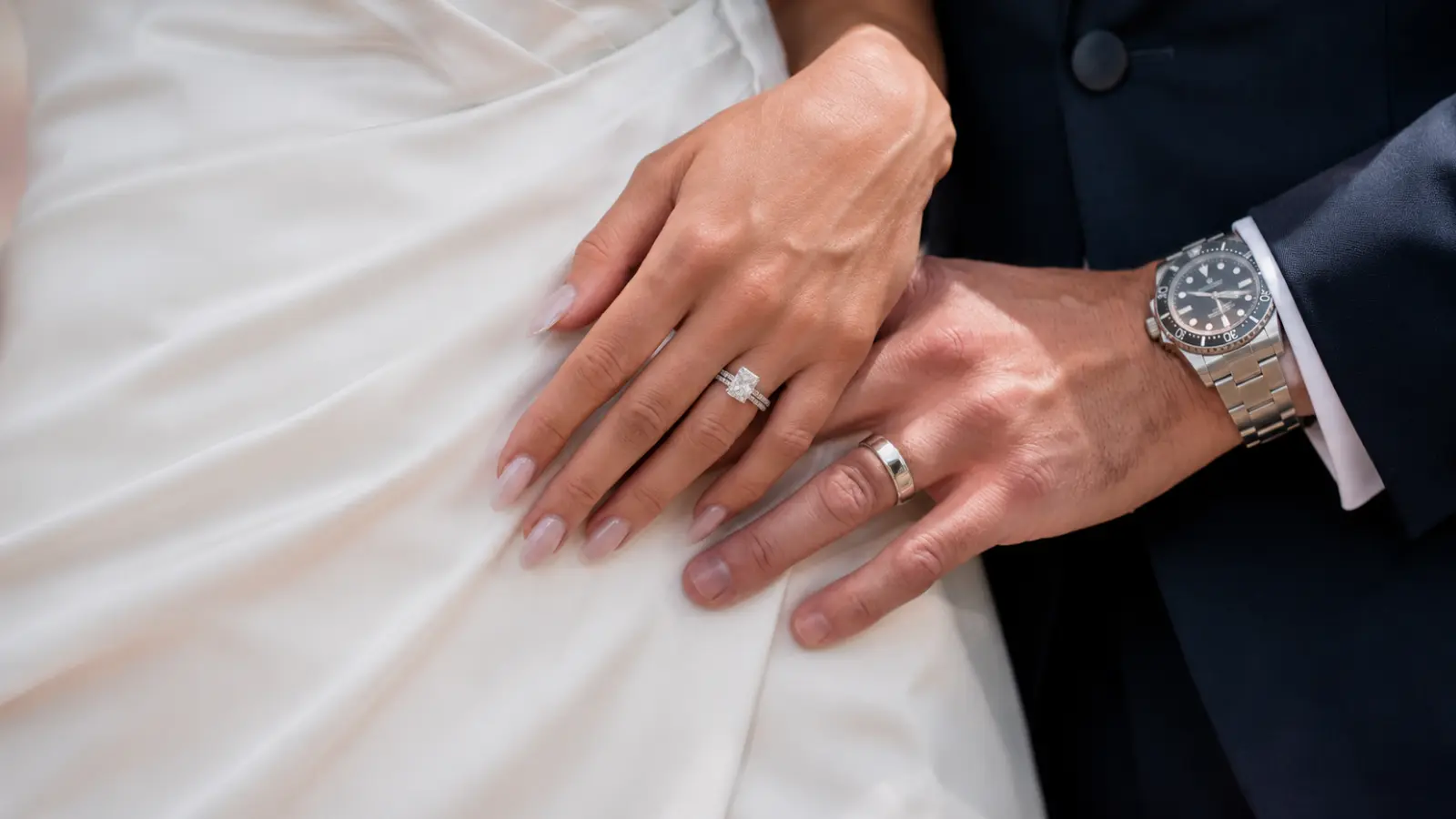 Bride and groom hands together showing their wedding rings, representing how couples wear their rings after marriage.