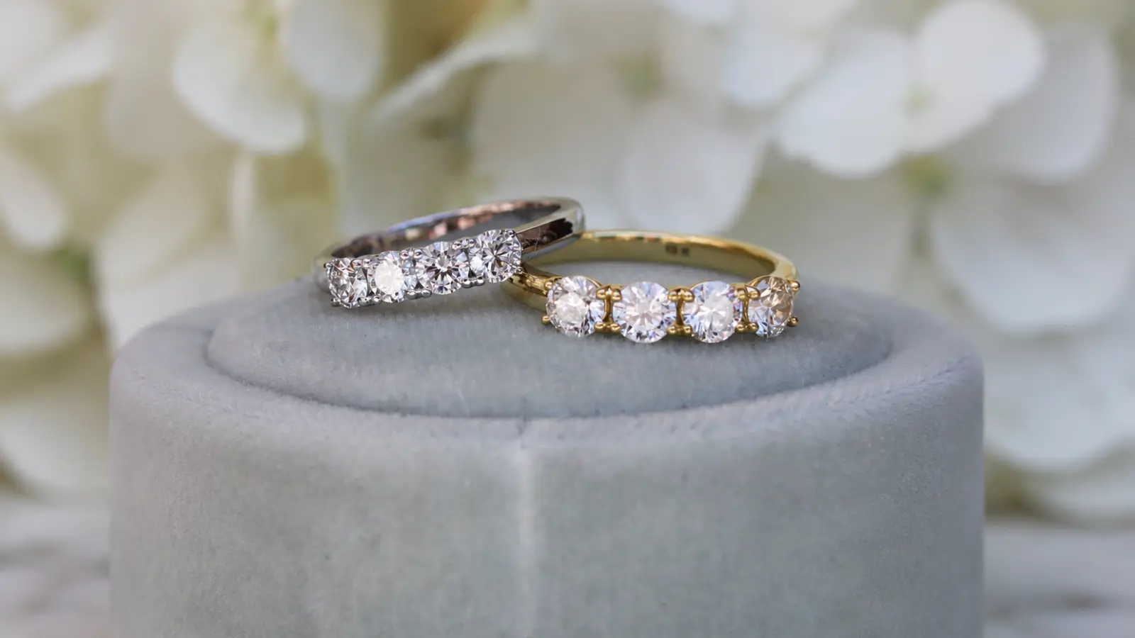 Yellow gold and white gold diamond wedding bands displayed on a velvet ring stand