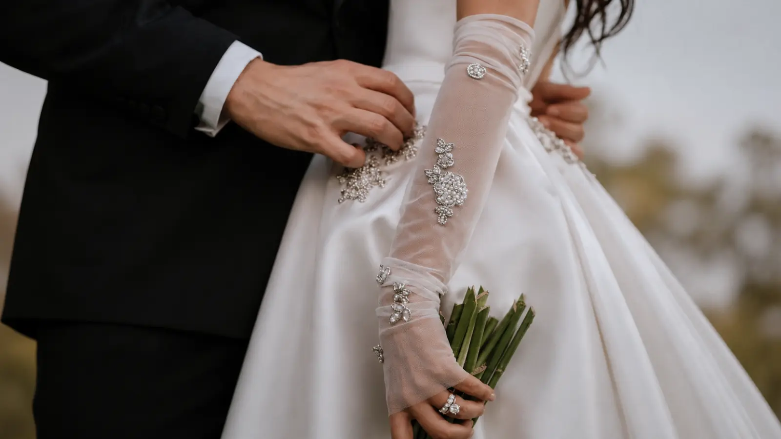 Bride wearing embellished fingerless wedding gloves with a bouquet, featuring decorative details and elegant wedding styling