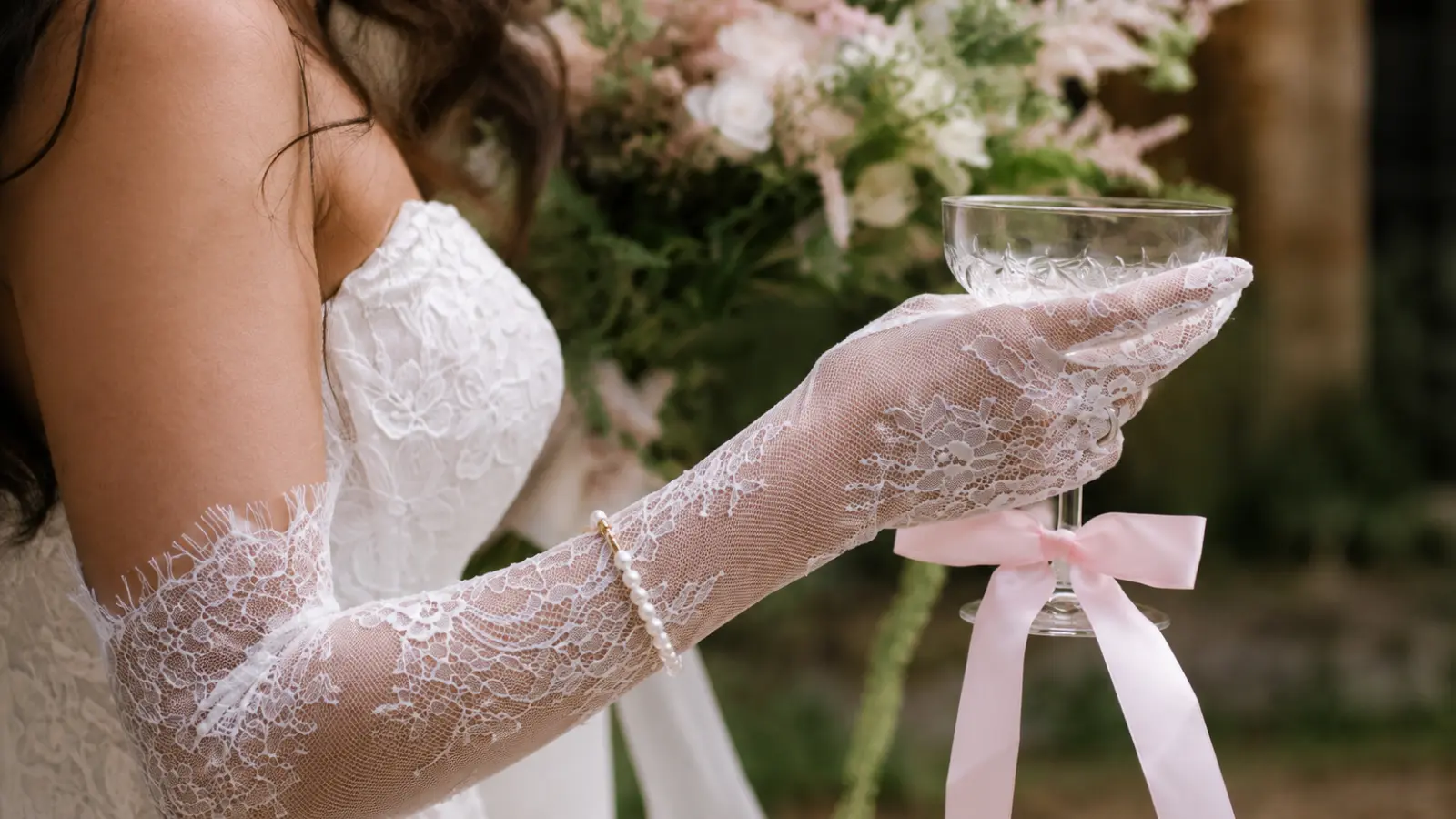 Bride wearing long lace bridal gloves with a wedding dress, featuring delicate fabric details and timeless bridal inspiration