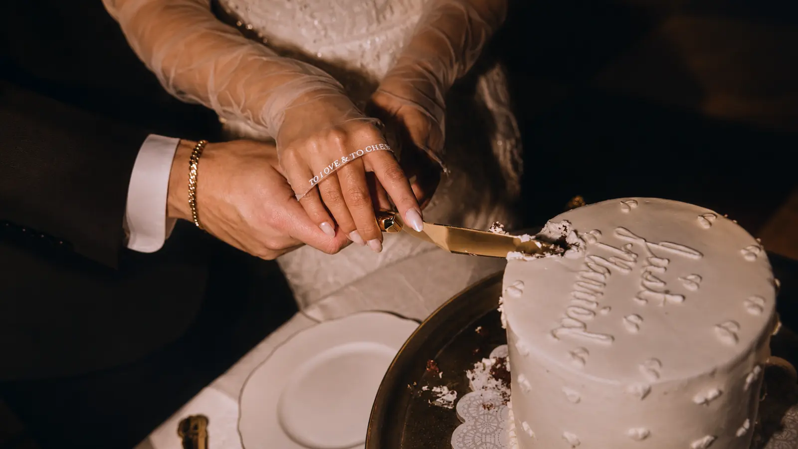 Modern white wedding cake being cut by the bride and groom