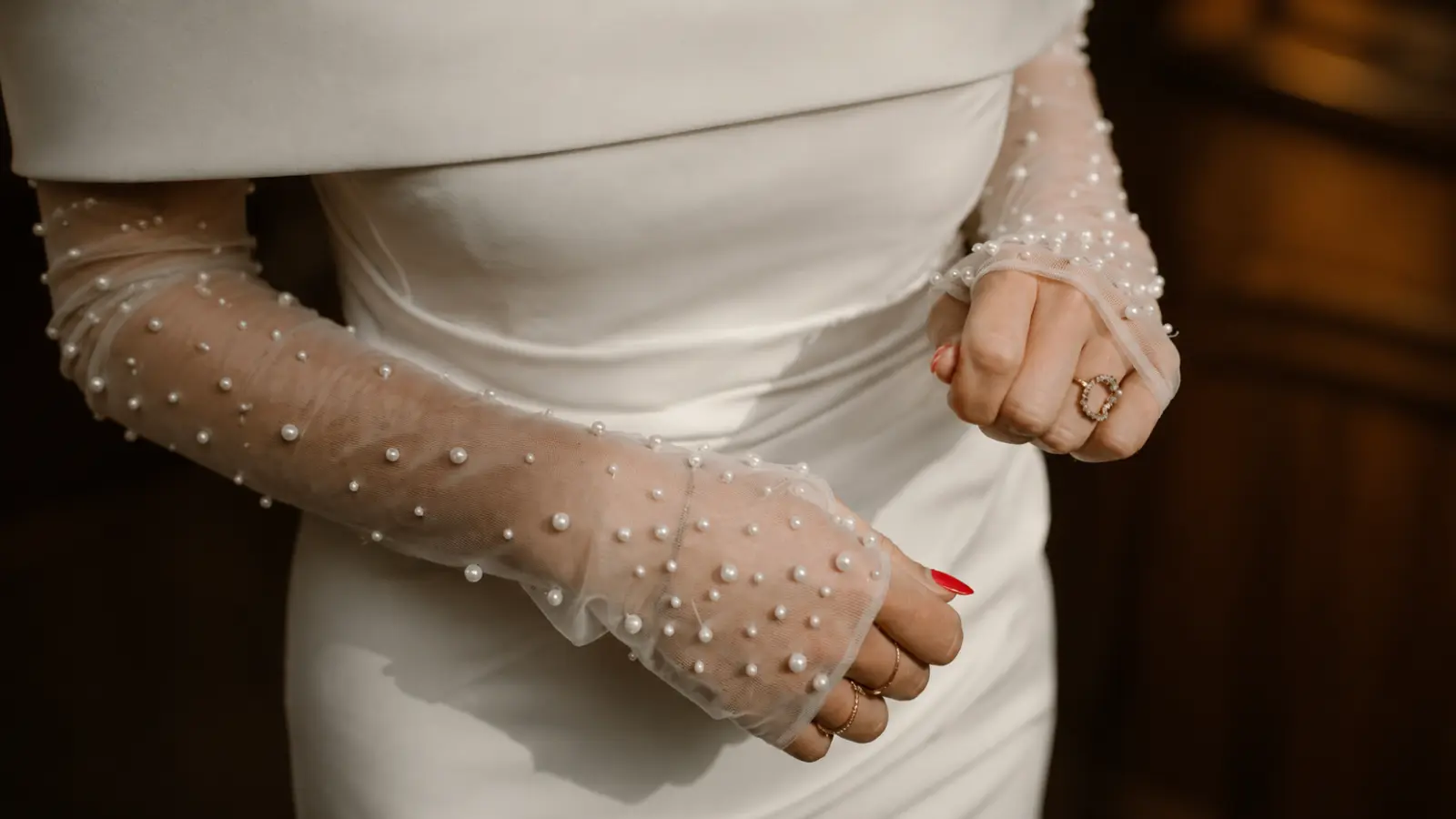 Close-up of pearl fingerless bridal gloves paired with a wedding dress, highlighting modern texture and delicate details