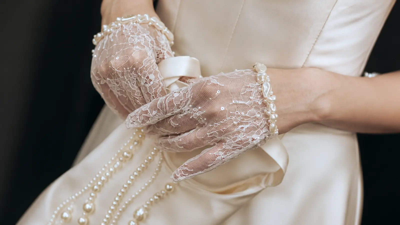 Detailed view of pearl lace bridal gloves paired with a wedding dress, featuring a romantic and timeless glove design