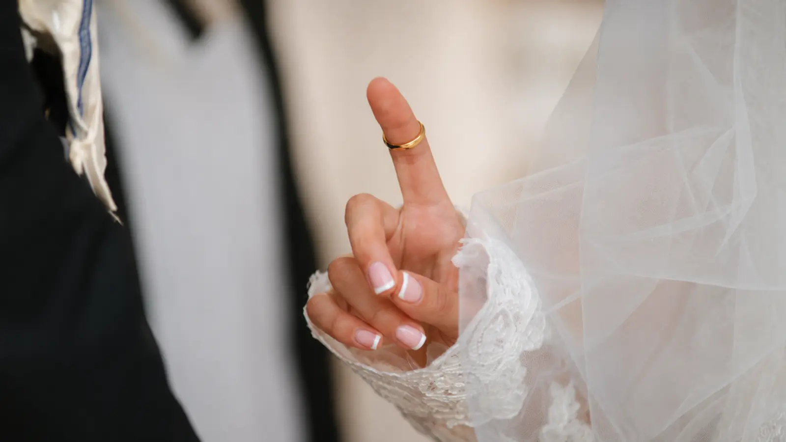 Wedding ring displayed on a bride’s hand with wedding attire, illustrating right hand and left hand wedding ring traditions.