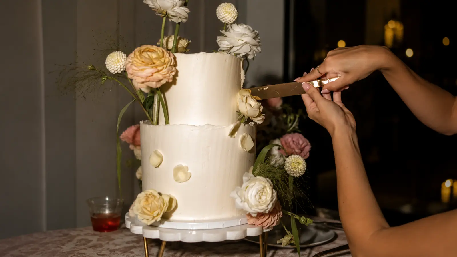 Floral wedding cake cutting moment with elegant flower details
