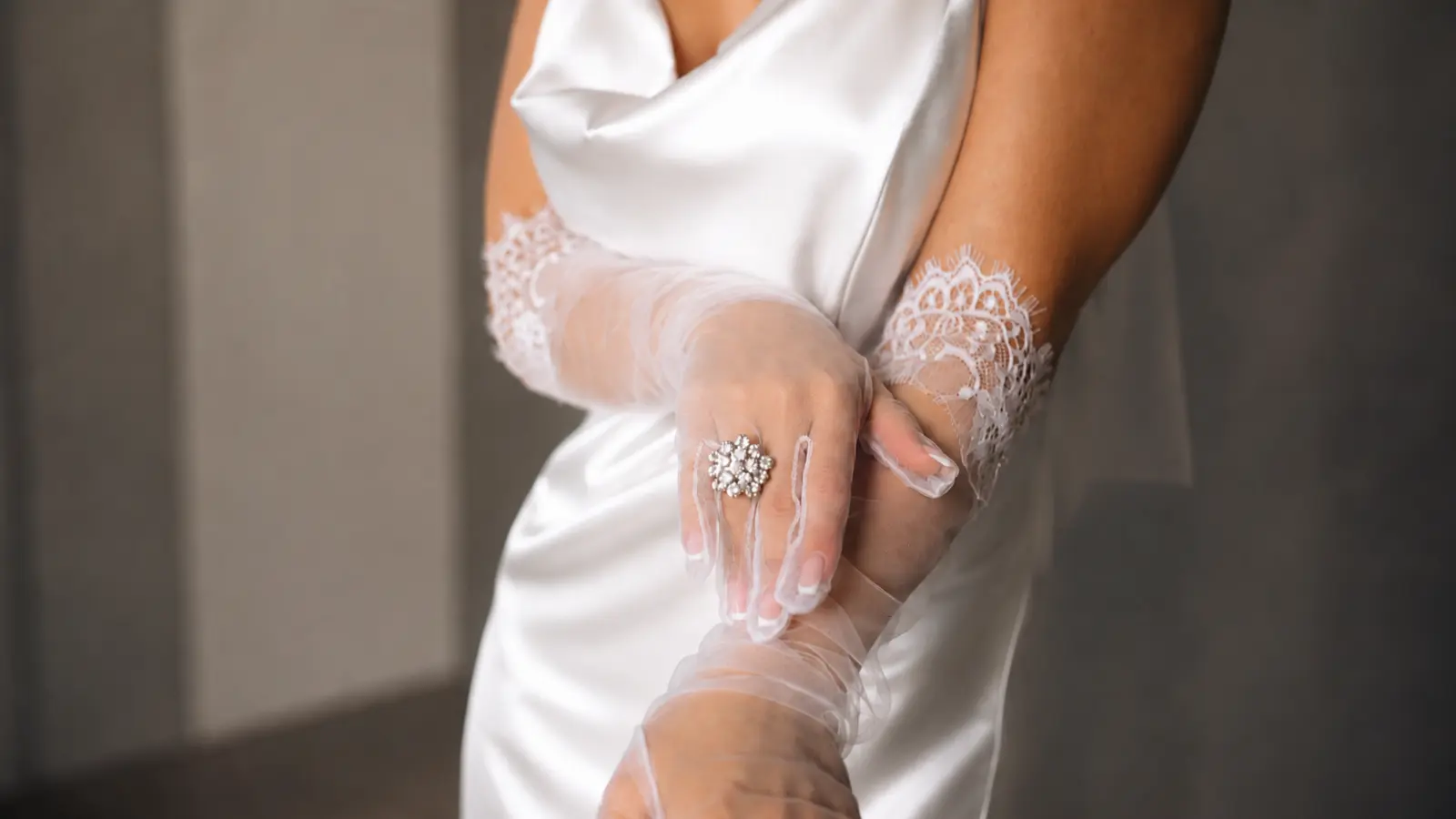 Close-up of sheer lace bridal gloves with a ring detail, highlighting modern wedding glove styling and delicate lace texture