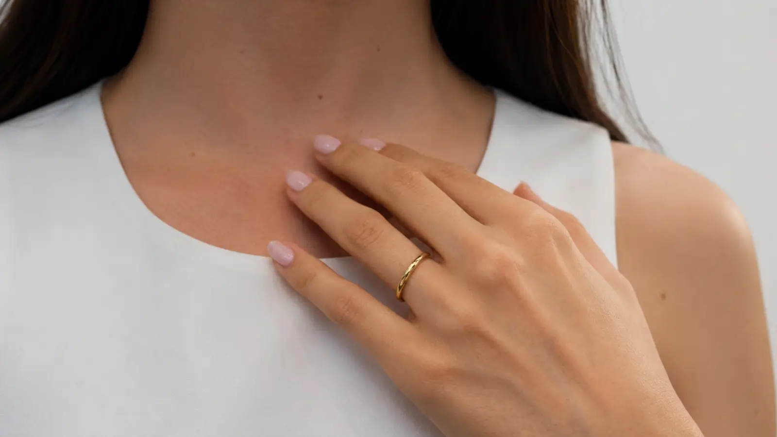 Close-up of a simple gold wedding band worn alone on a hand, representing a traditional wedding band style.