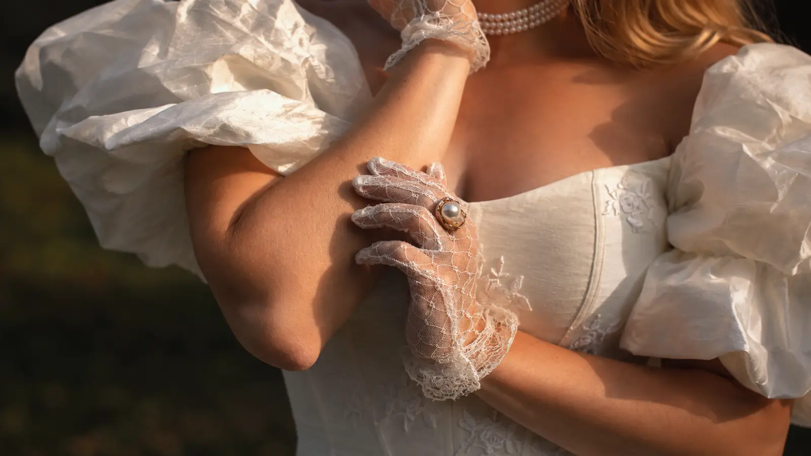 Close-up of lace wedding gloves with pearl jewelry on a bride, highlighting vintage bridal style and delicate glove details