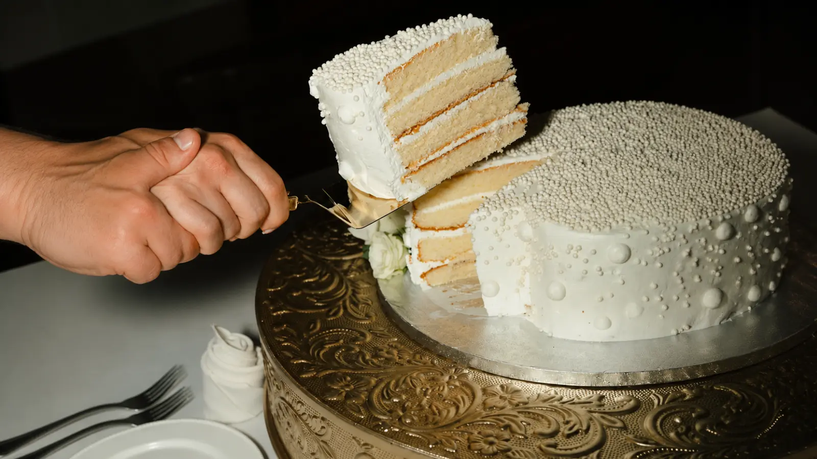 Close-up of a preserved wedding cake slice with visible cake layers and frosting after cutting into a saved wedding cake tier.