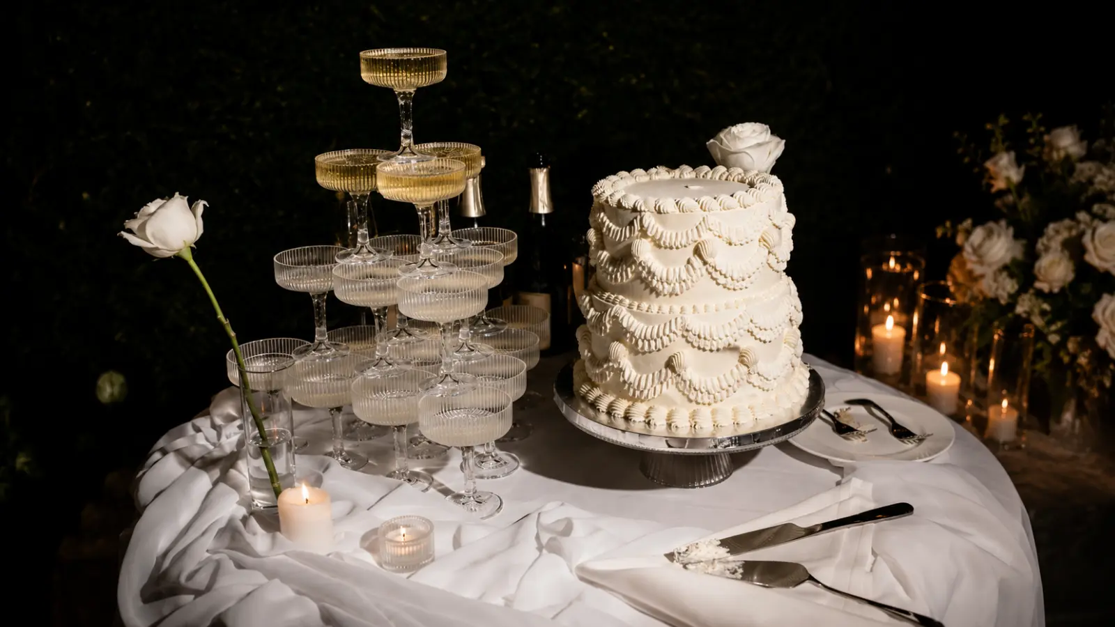 Wedding cake table with champagne tower, candles, and elegant reception decor