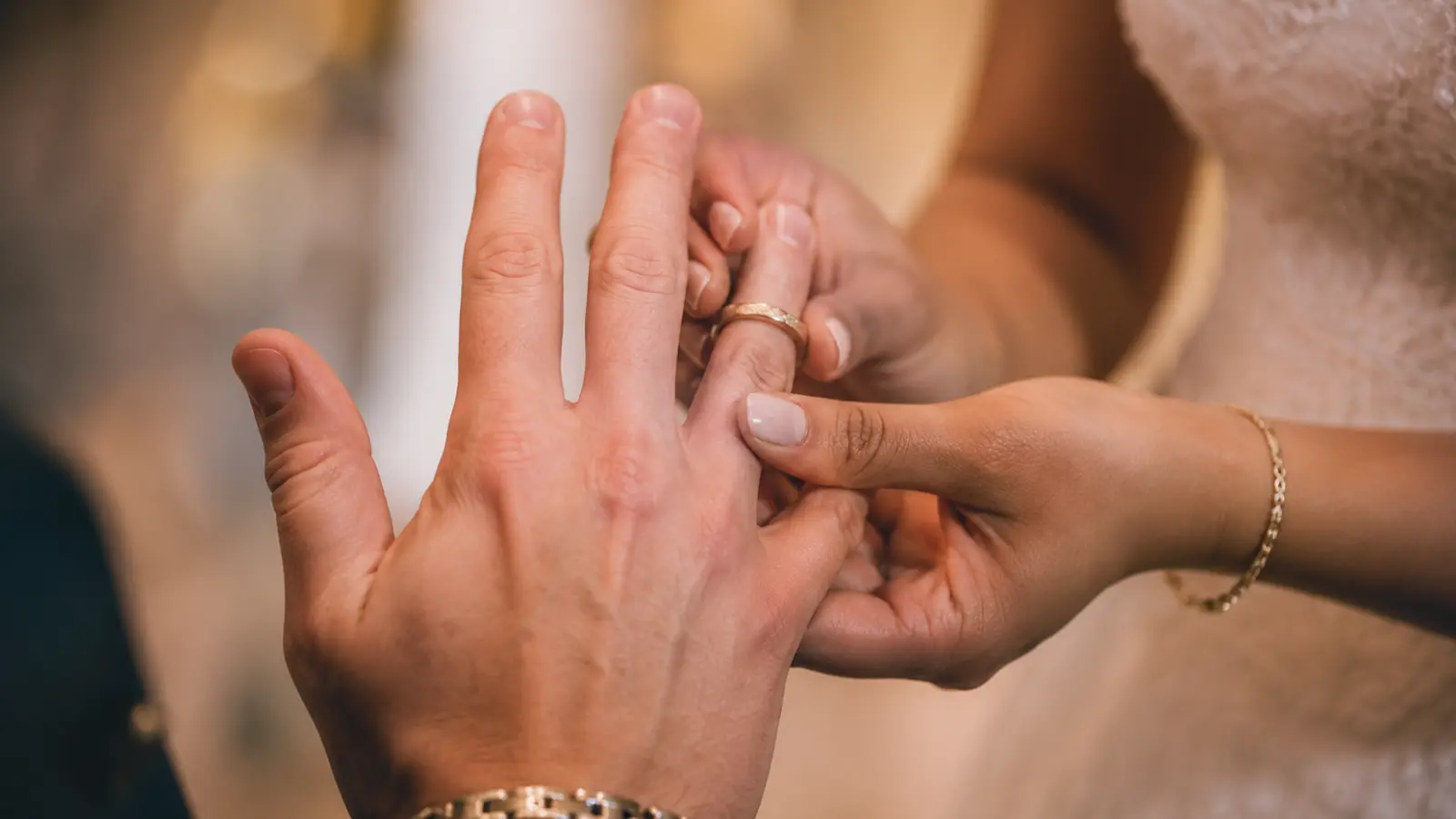 Bride placing a wedding ring on the groom’s finger during the ceremony, showing traditional wedding ring finger placement.