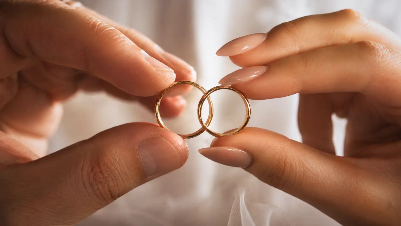 Close-up of two gold wedding bands held together to represent the timeless symbolism of eternity, unity, and everlasting marriage