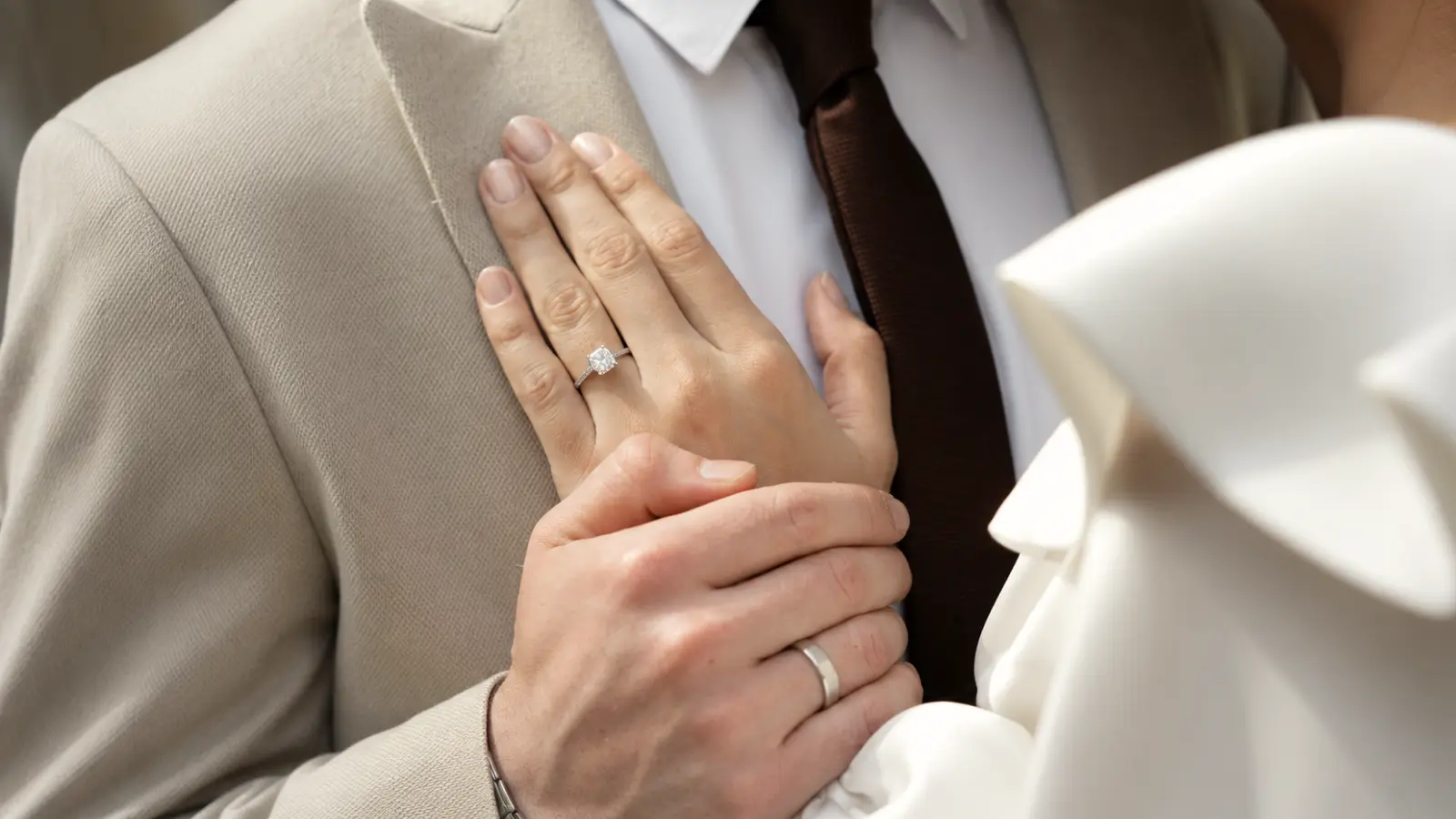 Bride embracing the groom with both wedding rings visible, highlighting the enduring symbolism of marriage, unity, and lifelong devotion