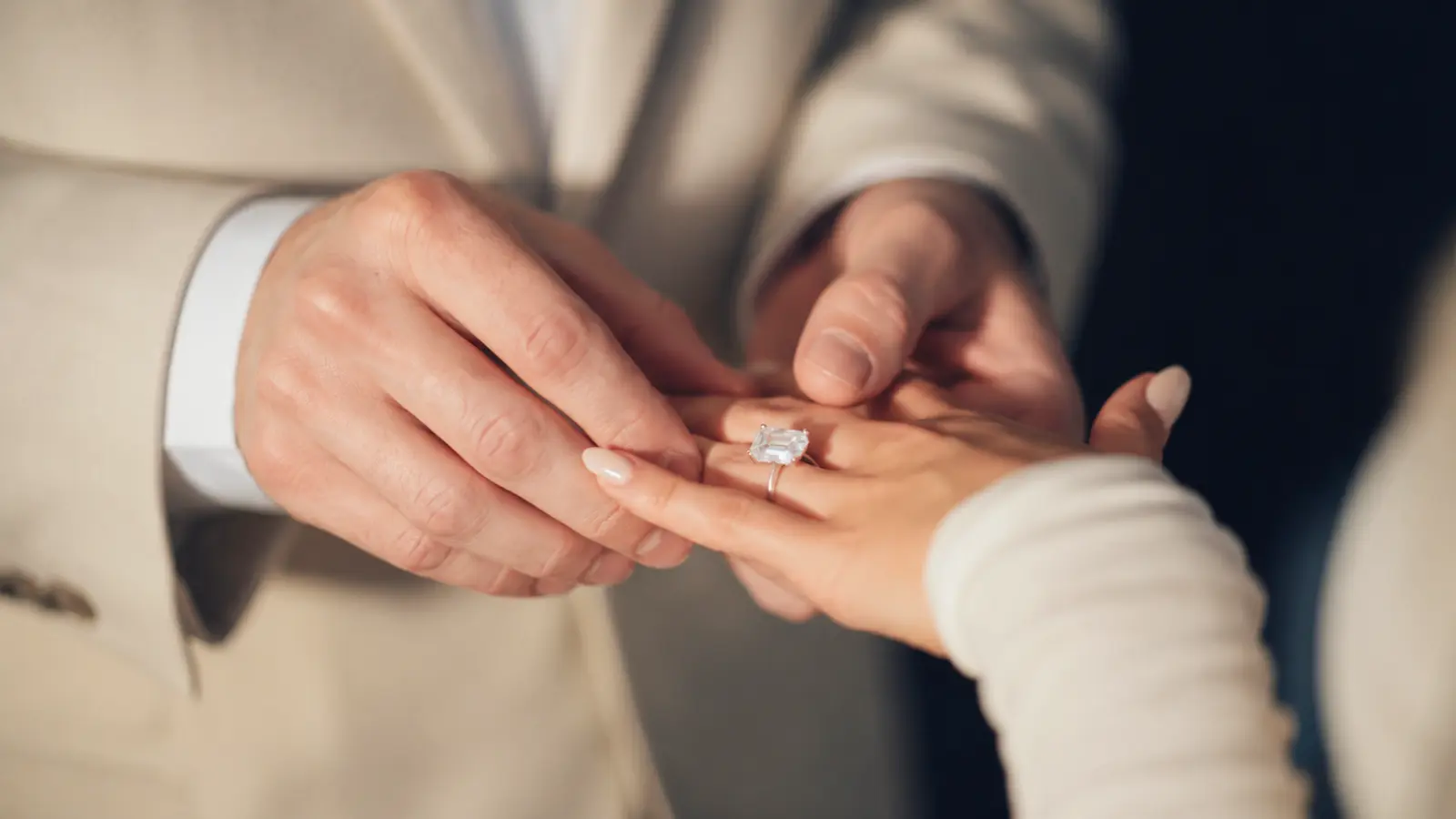 Groom placing a ring on the bride’s hand during a wedding moment, explaining which hand a wedding ring traditionally goes on and why.