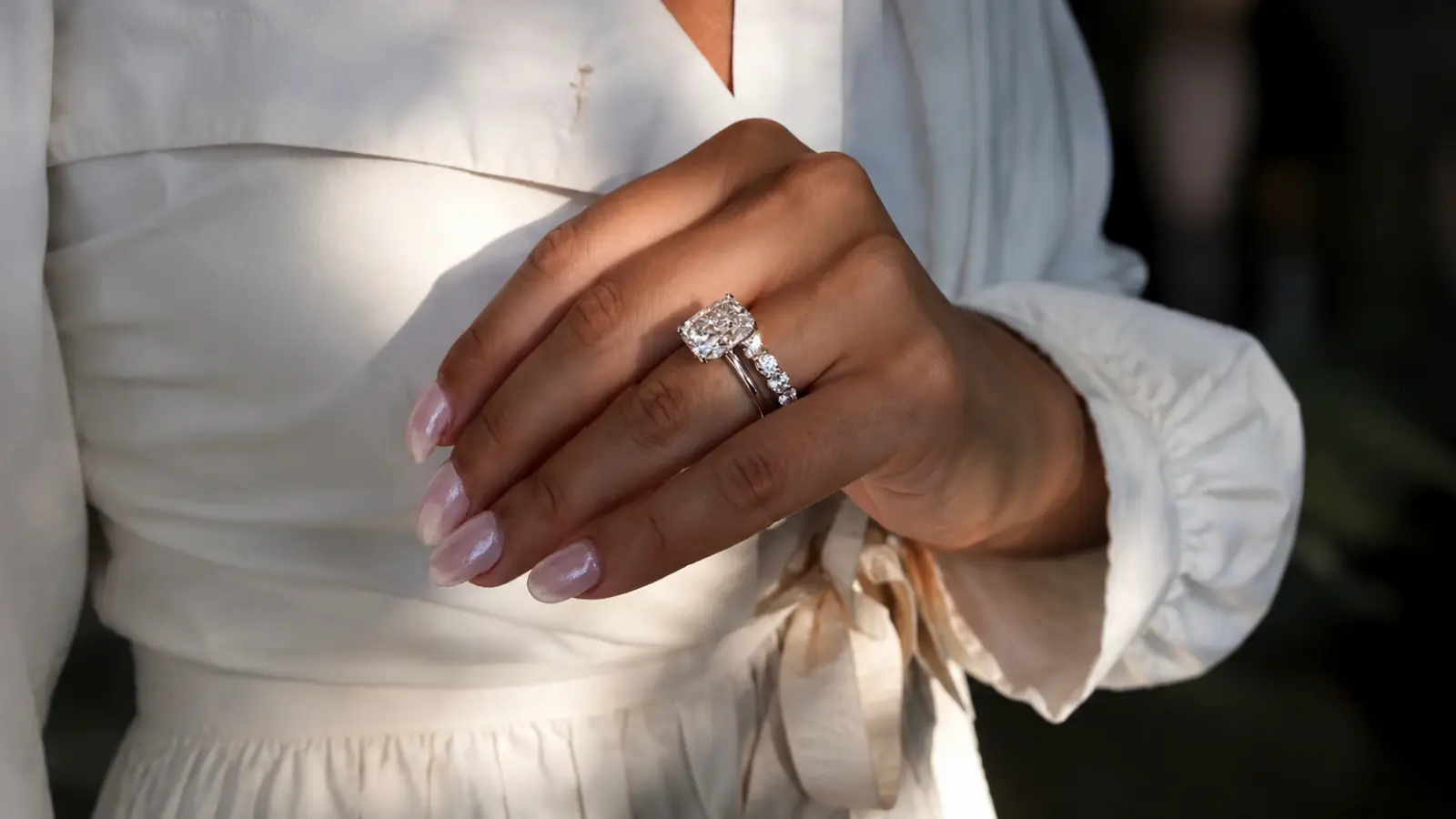 Close-up of a woman wearing a diamond eternity wedding band with a radiant-cut engagement ring