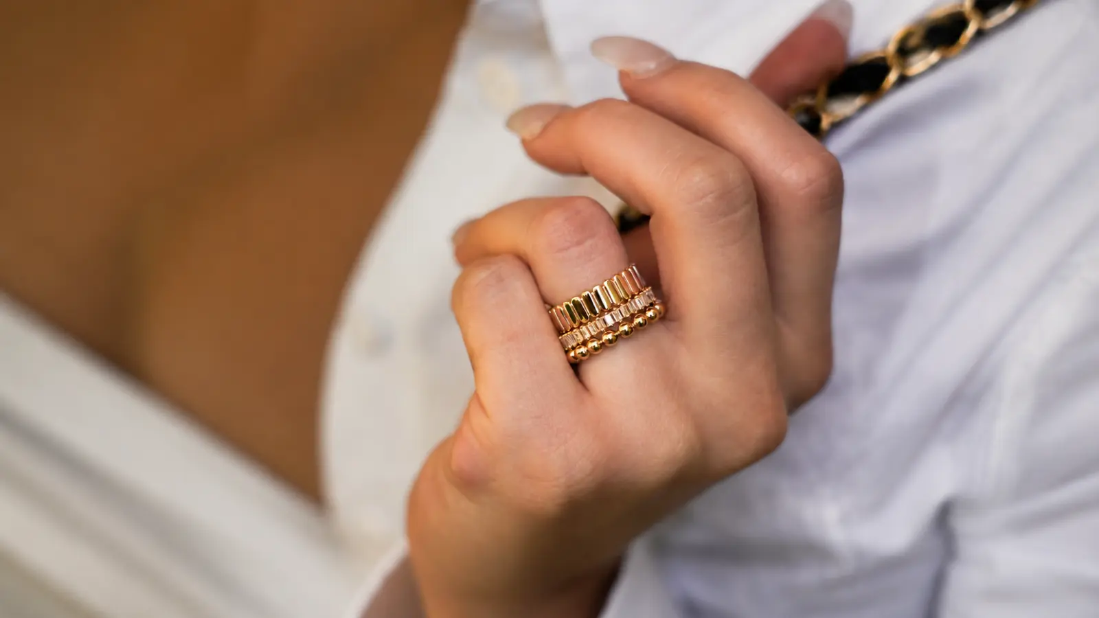 Woman wearing several stacked gold wedding bands with different textures and contemporary designs