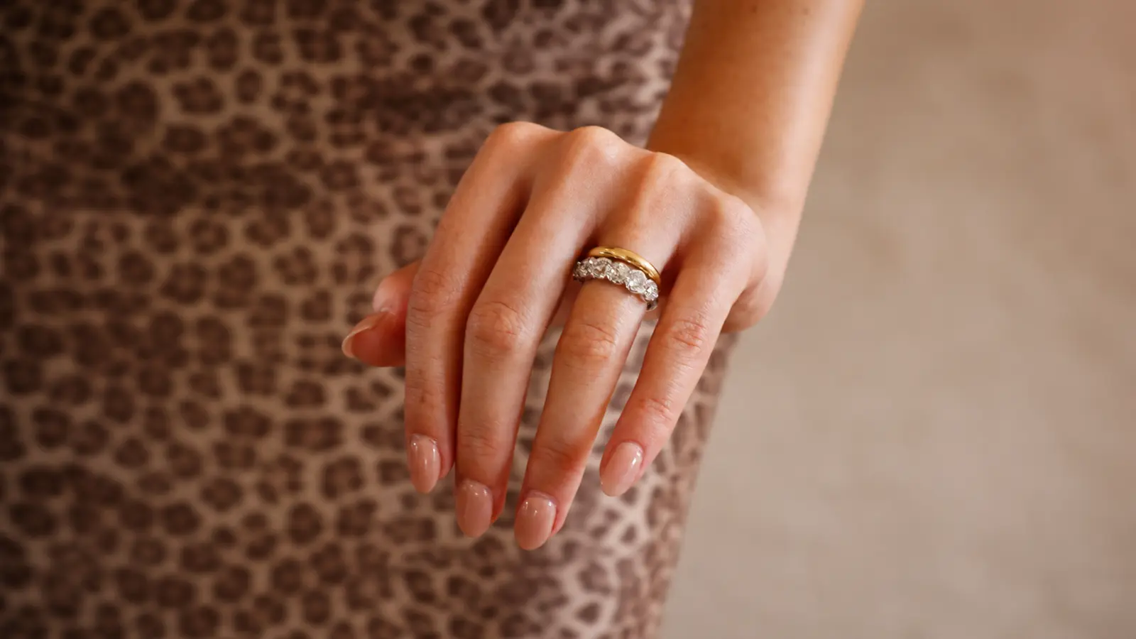 Woman wearing a polished yellow gold band stacked with a diamond eternity ring to create a personalized wedding ring look