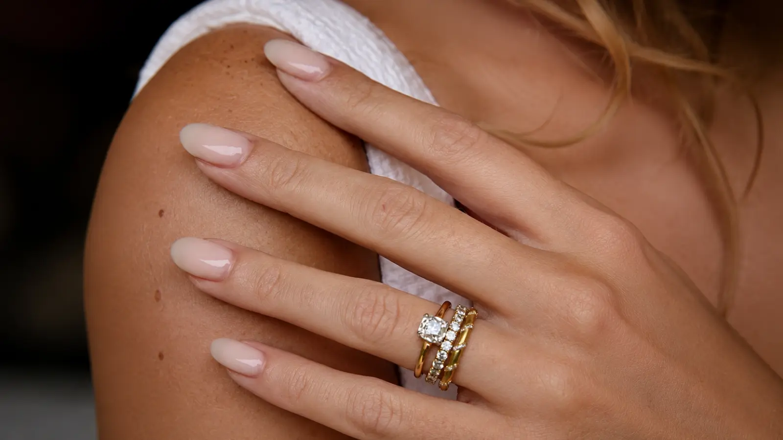 Close-up of a woman's hand wearing stacked diamond wedding bands and a solitaire engagement ring on her left ring finger