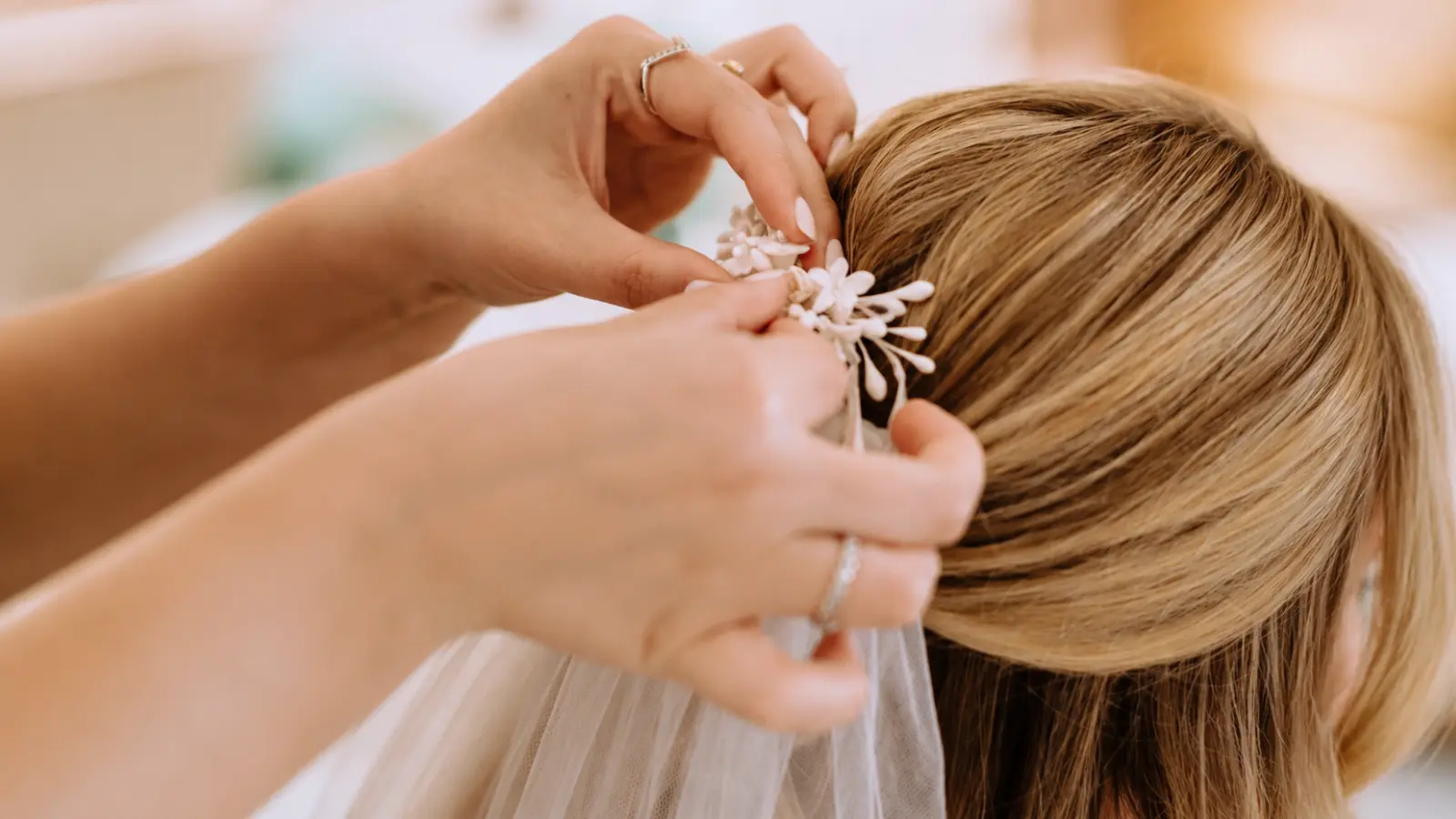 Close-up of hands attaching a wedding veil into a bridal hairstyle using a decorative hair accessory