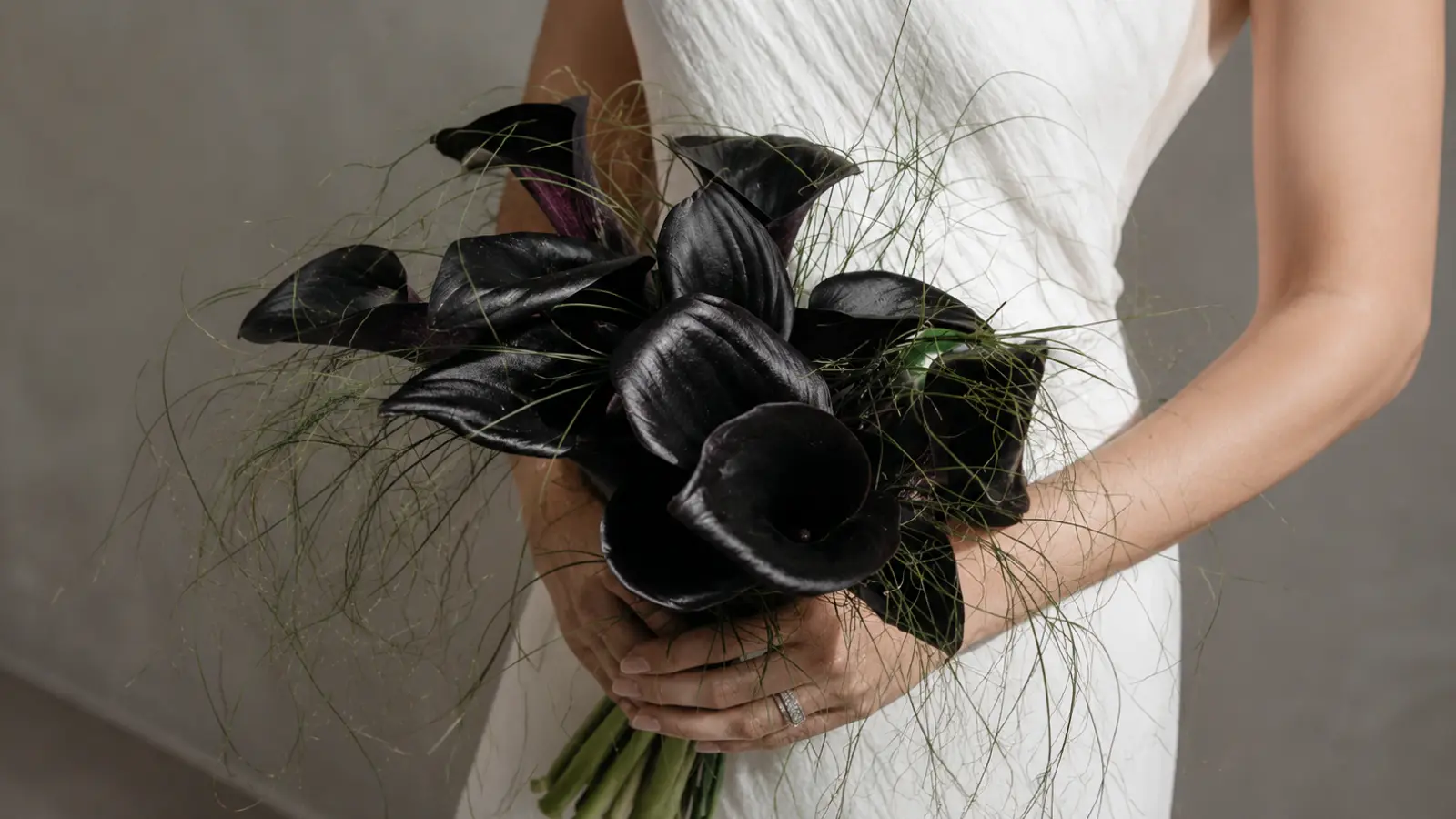 Bride holding a black artificial wedding bouquet made with real-touch calla lilies and delicate greenery