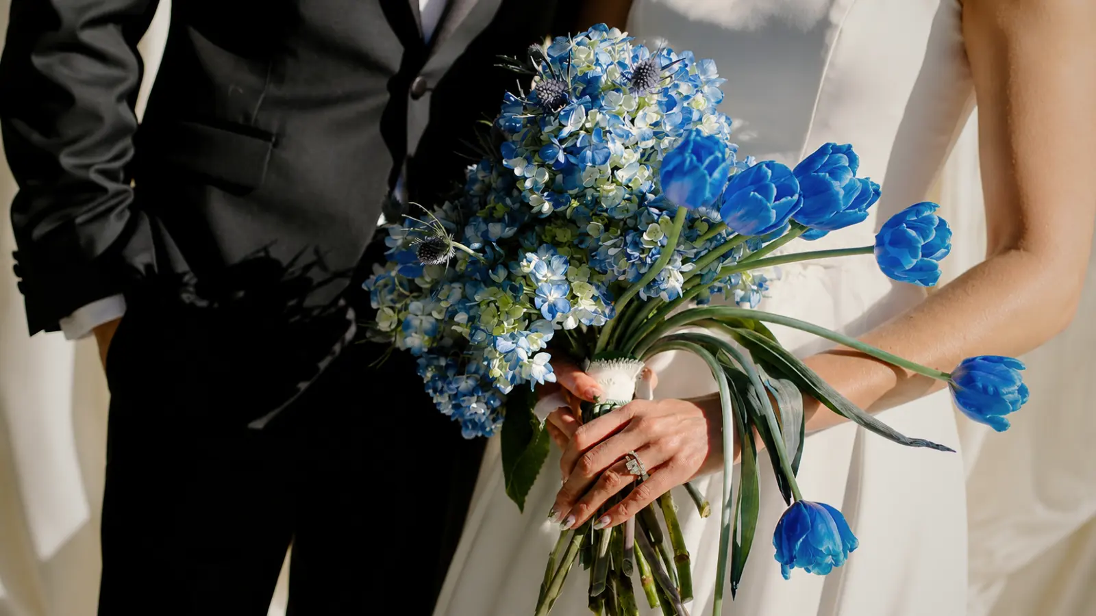 Bride holding a blue wedding bouquet with hydrangeas, blue tulips and thistle flowers.