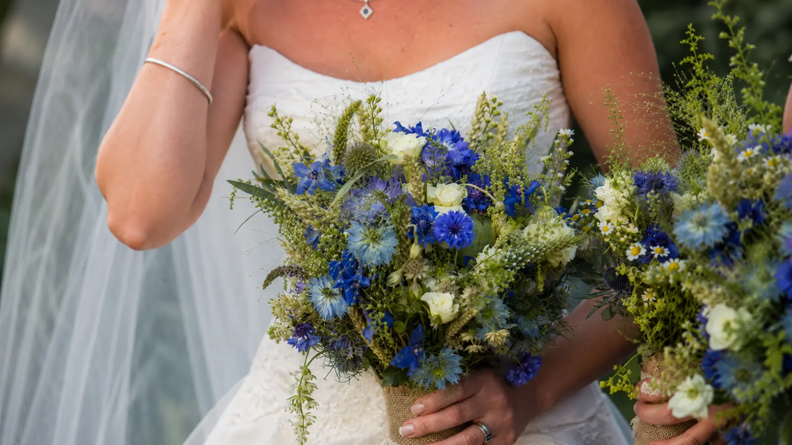 Bride holding a blue wildflower wedding bouquet with cornflowers and seasonal blooms