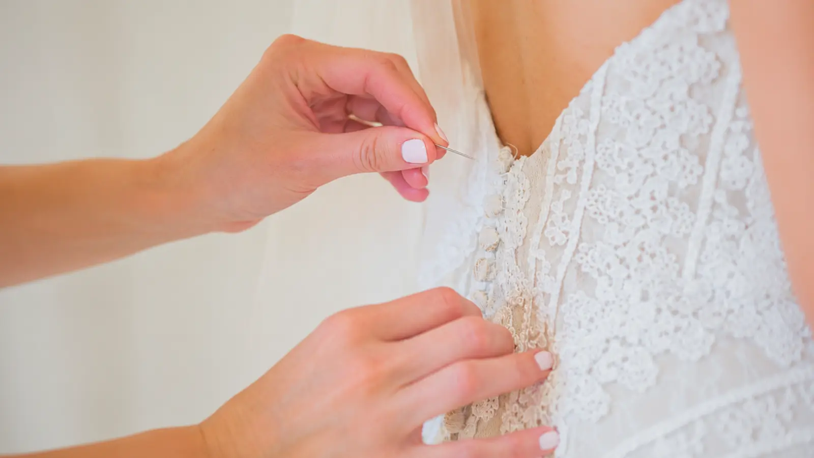 Wedding dress being repaired with a safety pin before the ceremony