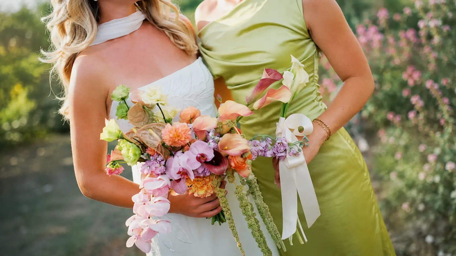 Bride and bridesmaid holding complementary modern wedding bouquets in different sizes