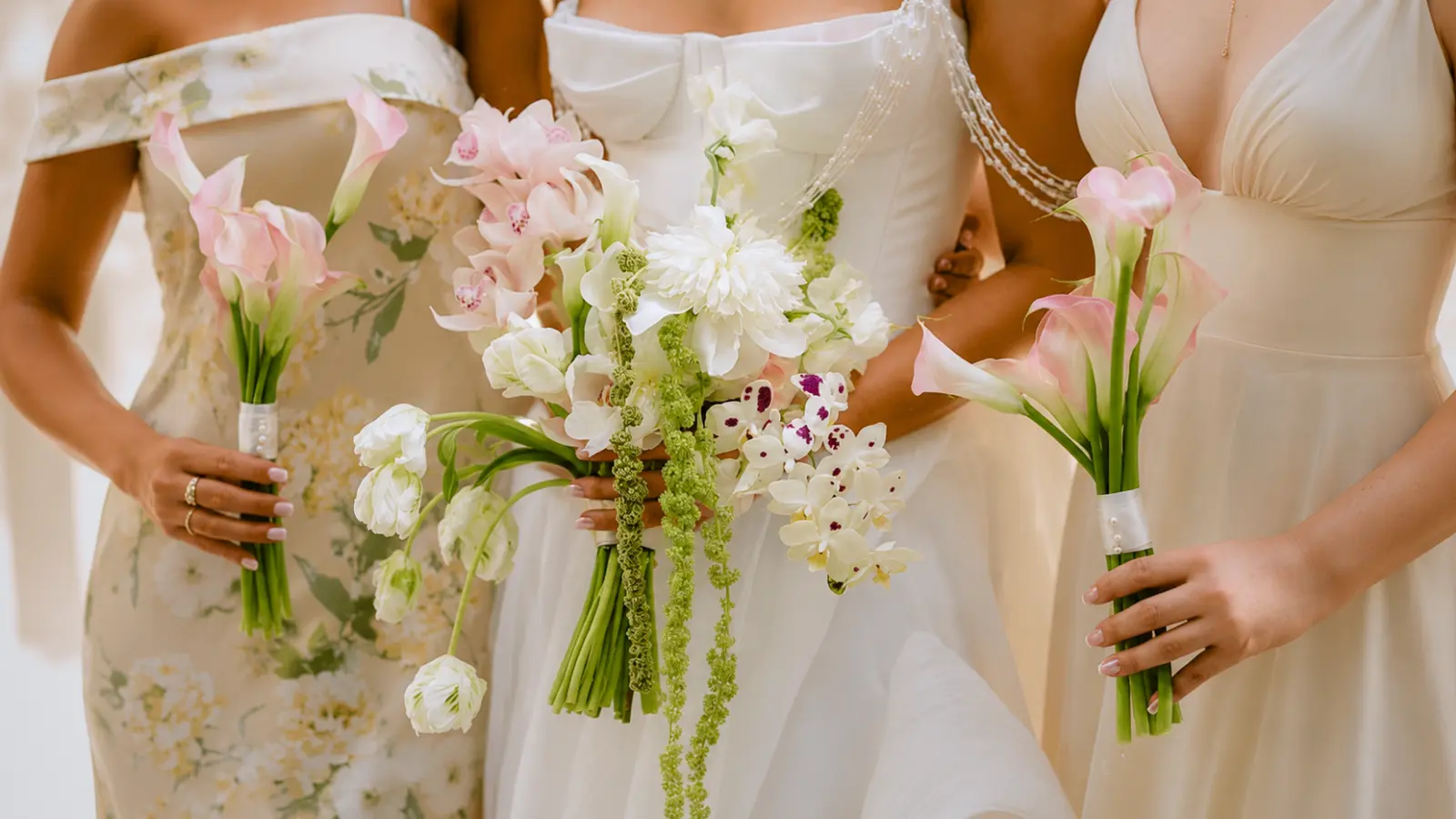 Bride and bridesmaids holding coordinated pastel wedding bouquets in different sizes