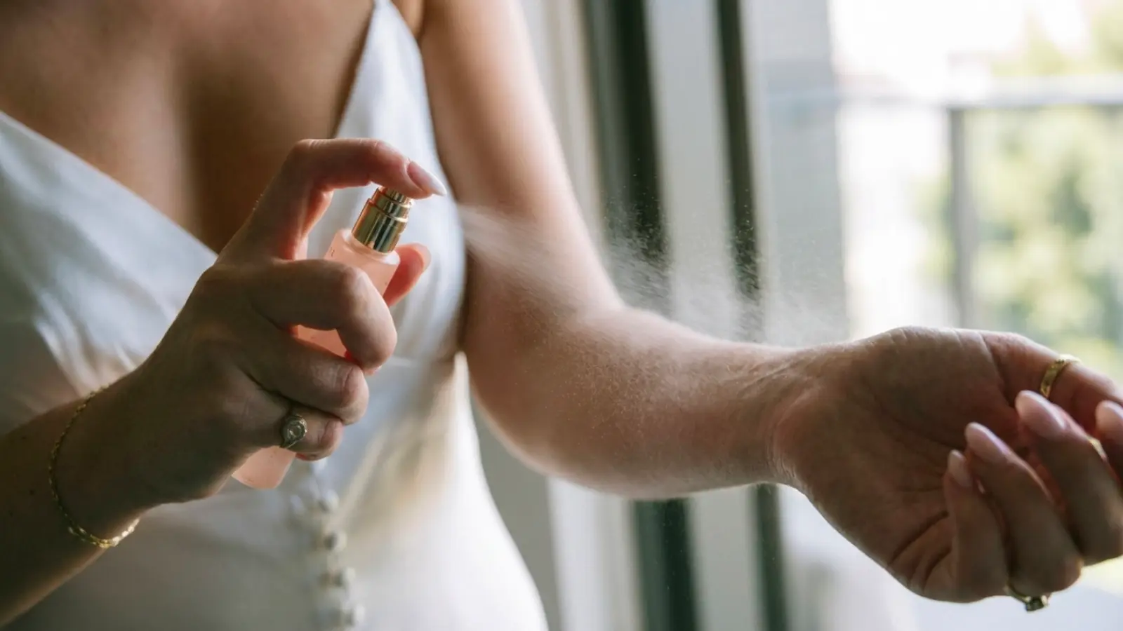 A bride applying bridal perfume to her pulse points before the ceremony, demonstrating the proper way to wear wedding fragrance for a long-lasting, elegant scent throughout the special day
