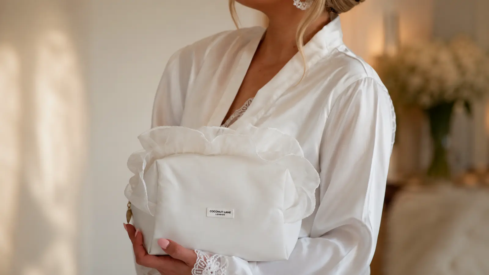 Bride in a white satin robe holding a spacious packed emergency kit before leaving for the wedding ceremony
