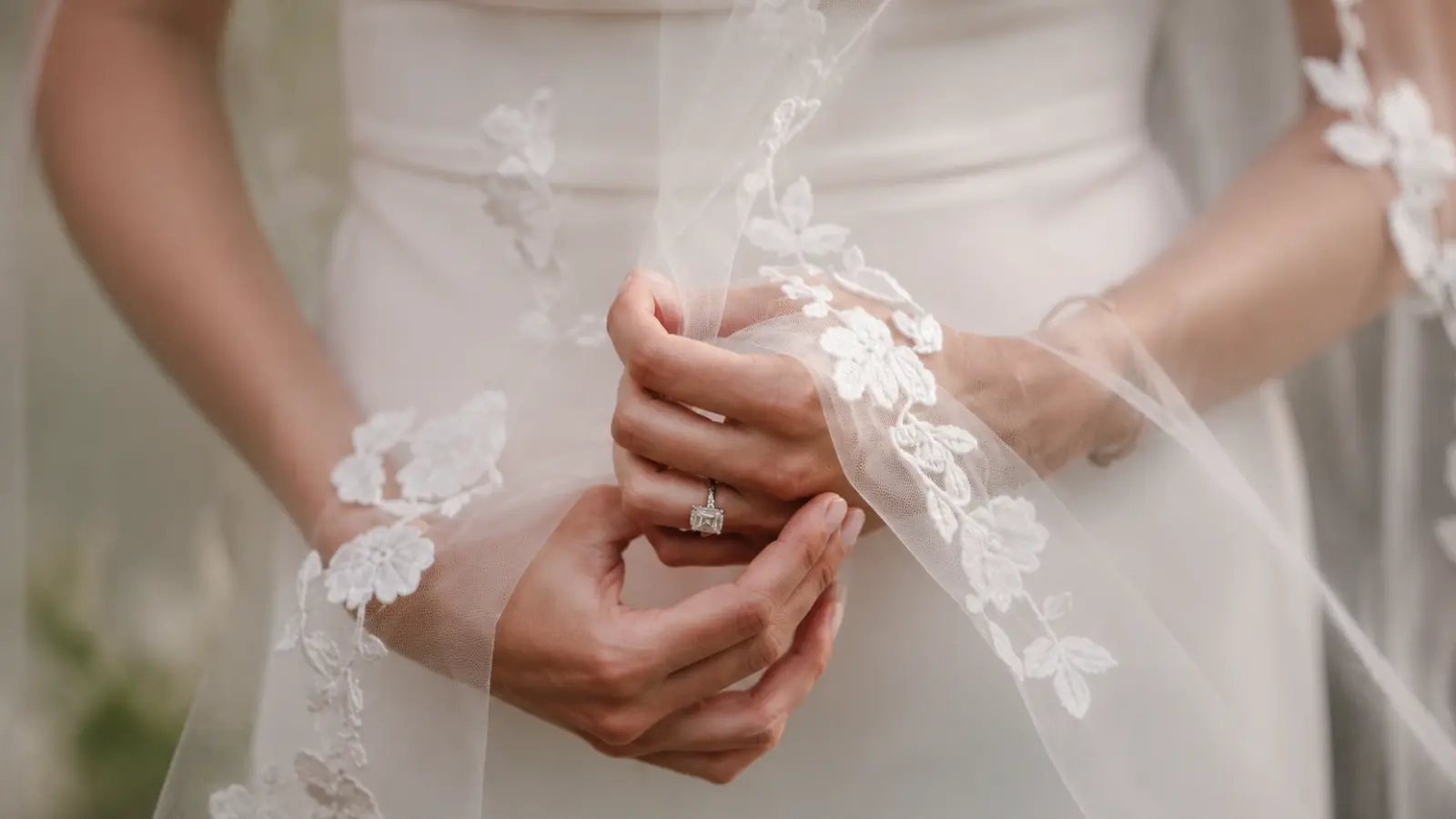 Bride holding a floral lace wedding veil with embroidered flowers, showcasing delicate tulle, intricate lace details, and elegant craftsmanship for a timeless bridal look