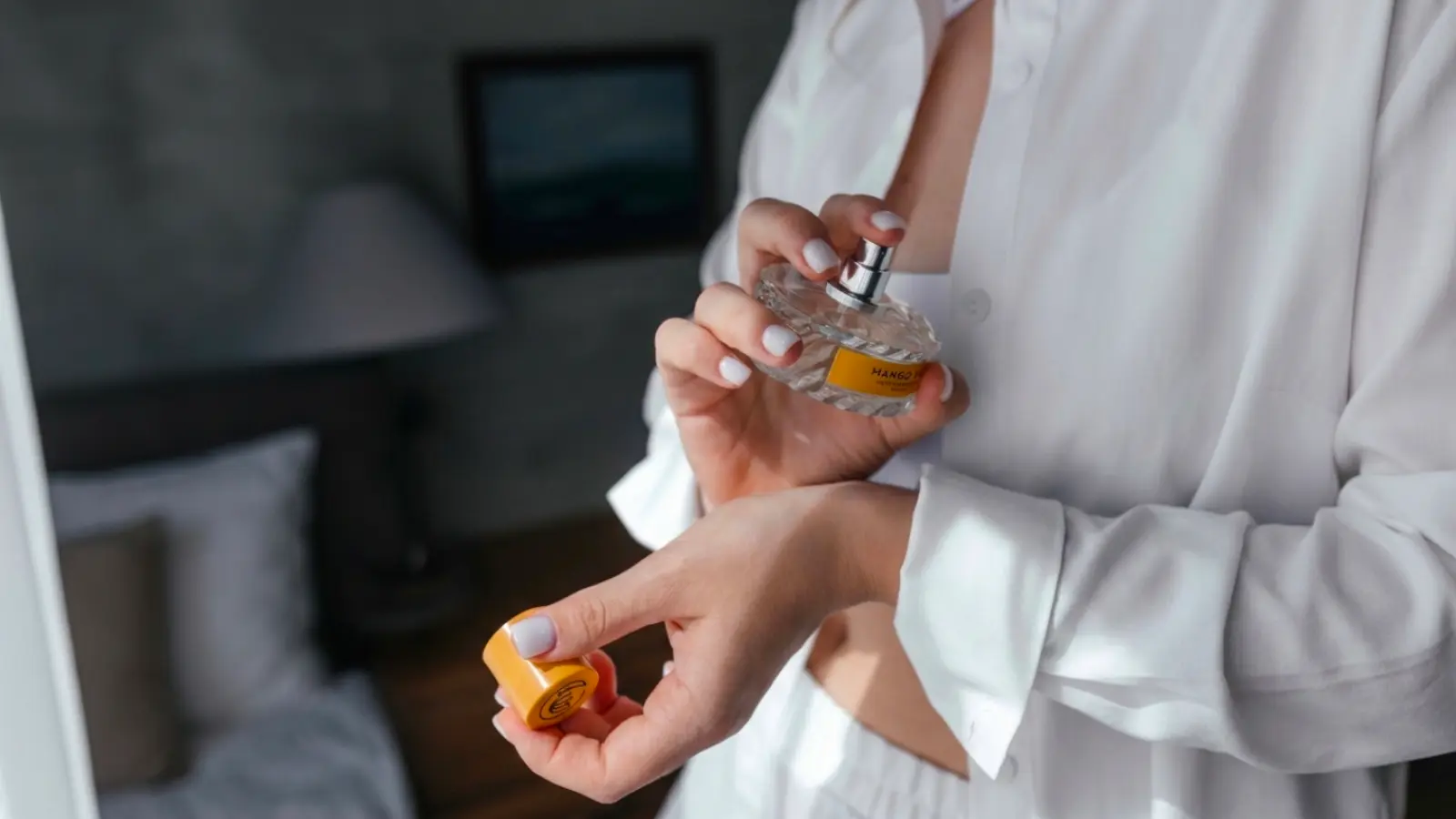 A bride spraying perfume onto her wrist while getting ready for the wedding, creating a signature fragrance memory that will remind her of the ceremony for years to come
