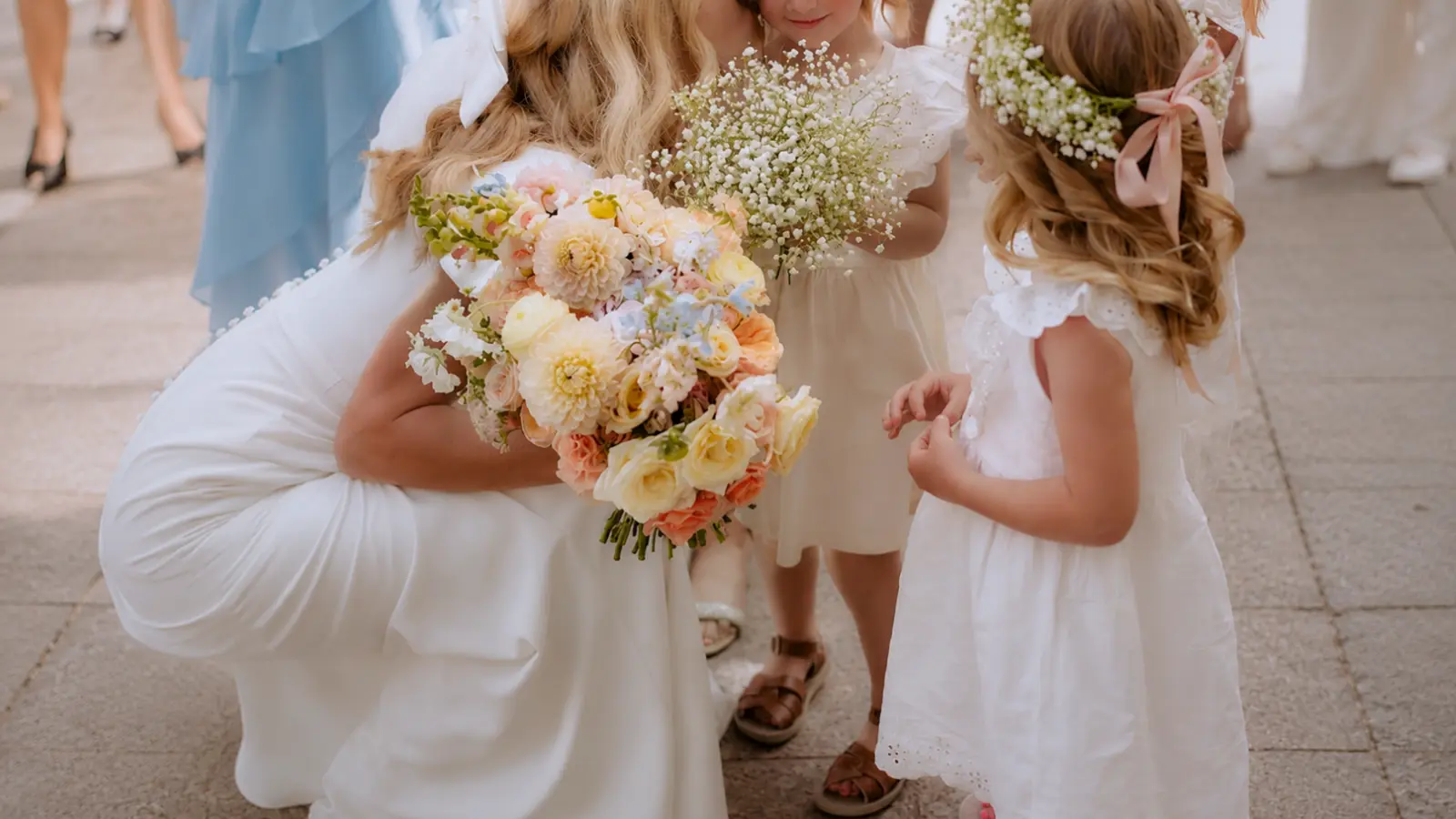 Bride holding her bouquet while talking with flower girls before the ceremony